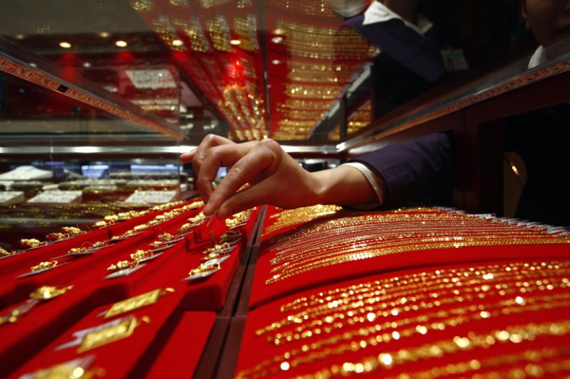 © Reuters. A vendor removes a gold accessory from a glass case at a jewellery shop in Suining