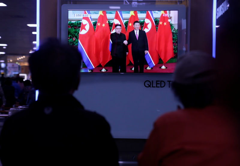 © Reuters. Un'immagine in tv dell'incontro tra il leader nordcoreano Kim Jong Un e il presidente cinese Xi Jinping