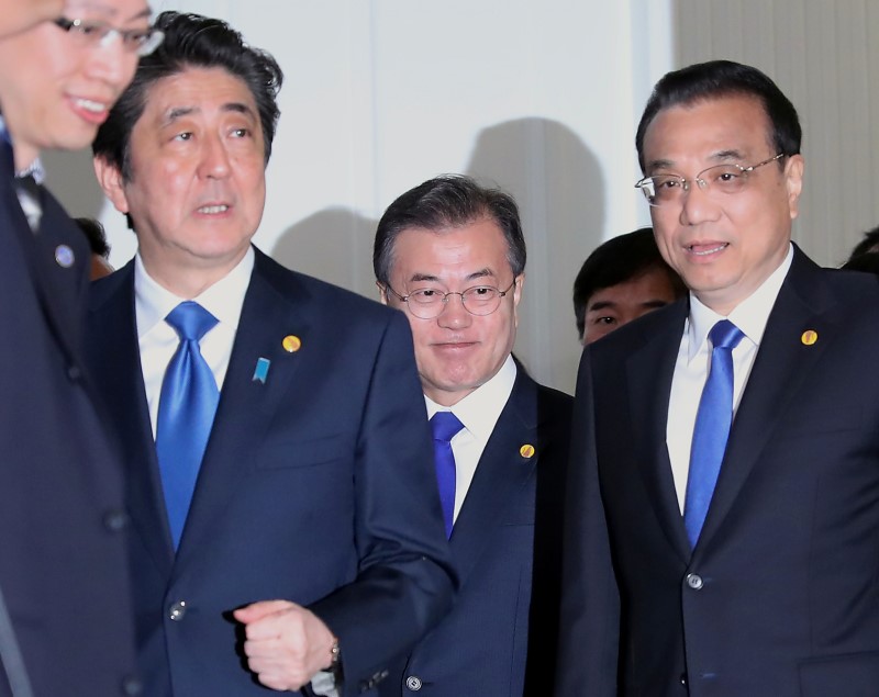 © Reuters. Chinese Premier Li Keqiang, Japanese Prime Minister Shinzo Abe and South Korean President Moon Jae-in walk together to their summit in Tokyo