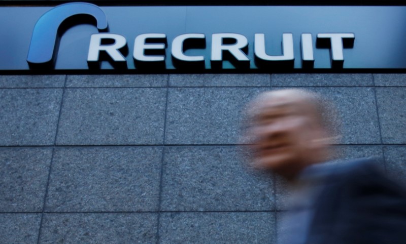 © Reuters. FILE PHOTO: A pedestrian walks under the logo of Recruit Holdings in front of its headquarters building in Tokyo