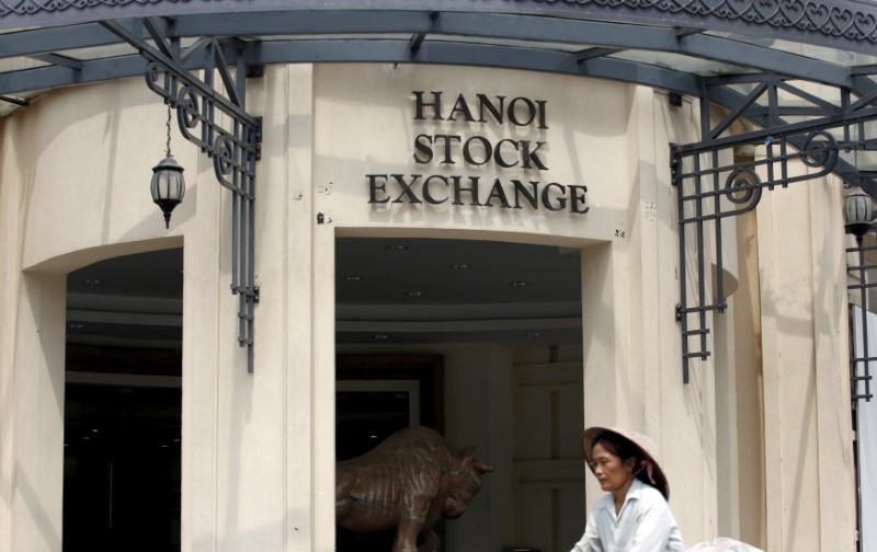 © Reuters. FILE PHOTO: A woman rides a bicycle past a Stock Exchange center in Hanoi