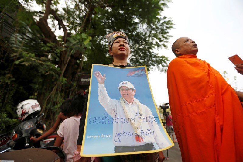 © Reuters. Supporters of Kem Sokha, former opposition leader and ex-president of the now-dissolved Cambodia National Rescue Party (CNRP), hold up a poster near the Appeal Court in Phnom Penh, Cambodia