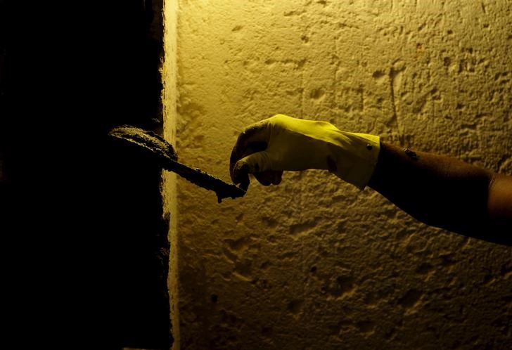 © Reuters. Trabalhador aplica cimento na parede