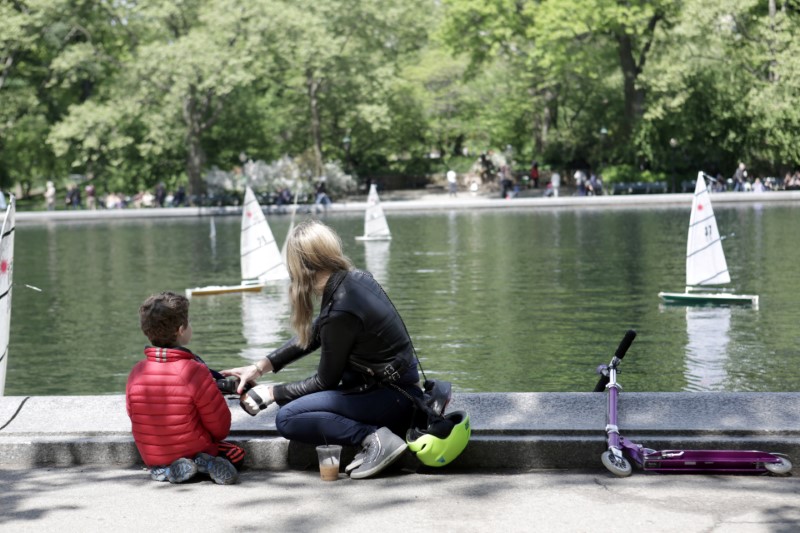 © Reuters. A woman and a child look at miniature sailboats on Mother's Day in Central Park, New York City