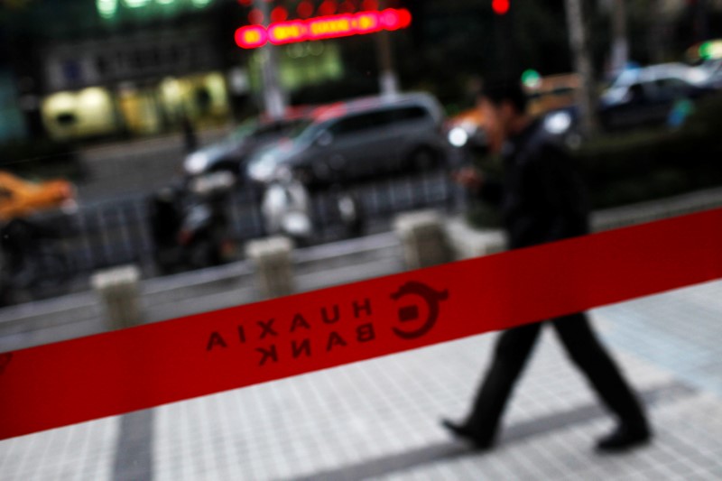 © Reuters. FILE PHOTO: A man walks past a Hua Xia Bank branch in Shanghai