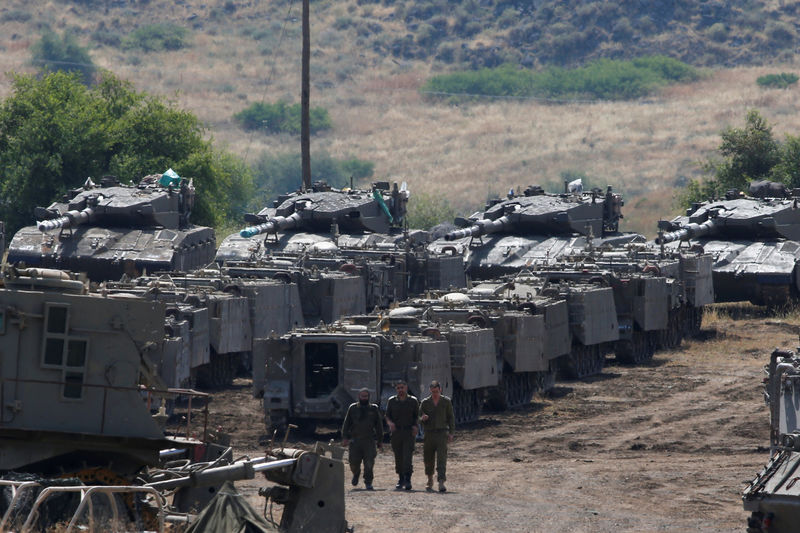 © Reuters. Israeli soldiers walk among armored vehicles in the Israeli-occupied Golan Heights