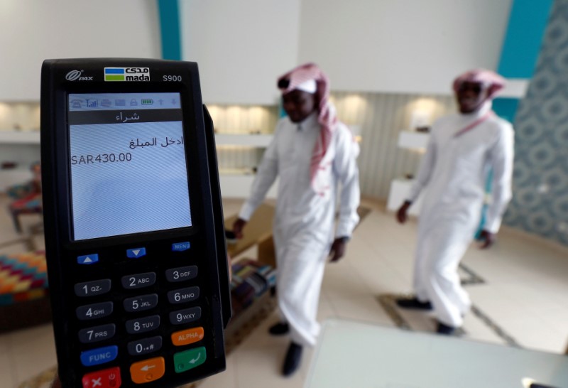 © Reuters. FILE PHOTO: A credit card machine is seen as Saudi men shop in a store in Riyadh