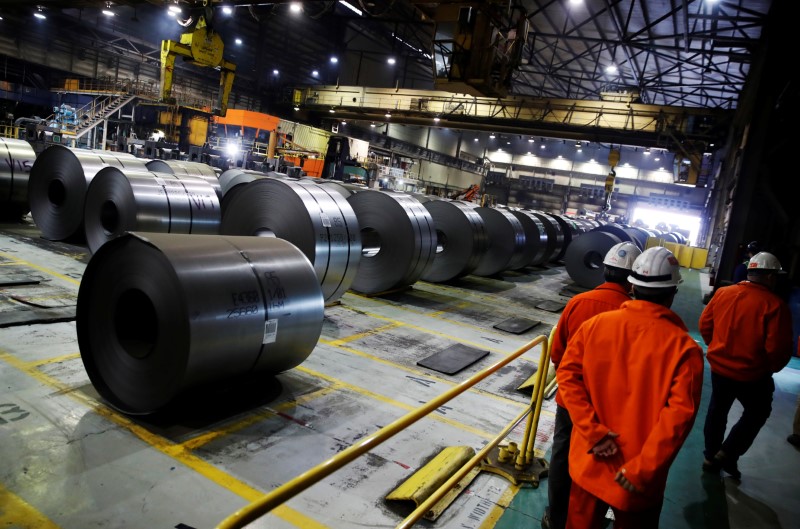 © Reuters. Workers walk by rolled up steel sits in the ArcelorMittal Dofasco steel plant in Hamilton, Ontario