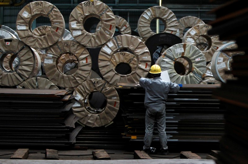 © Reuters. FILE PHOTO - A worker checks steel coils and steel sheets at a distribution warehouse in Urayasu, east of Tokyo
