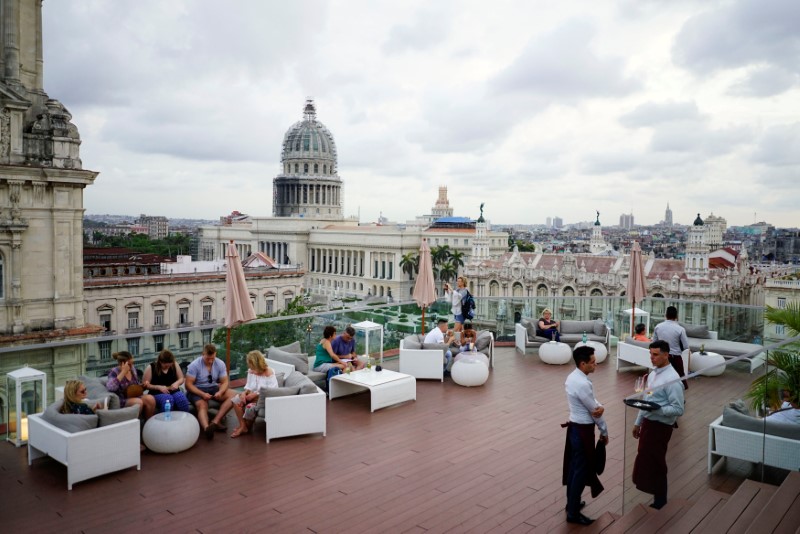 © Reuters. Tourists enjoy a rooftop of a recently renovated Belle Epoque shopping mall housing the Gran Hotel Manzana in the top floors and luxury stores on the ground floor in Havana