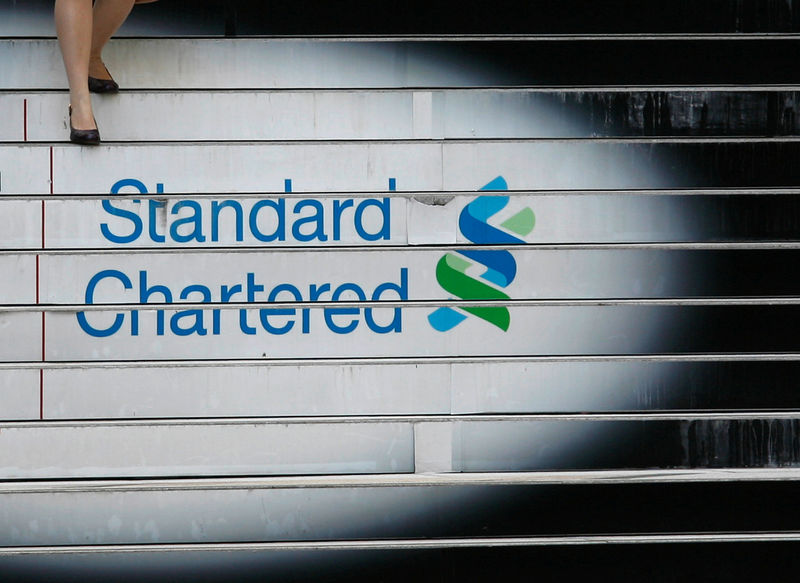 © Reuters. FILE PHOTO: A woman walks down the stairs of the Standard Chartered headquarters in Hong Kong