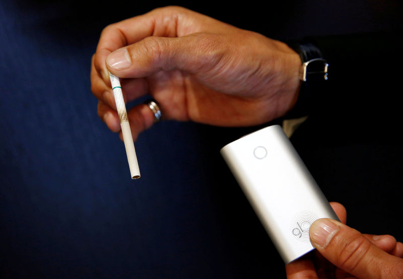 © Reuters. FILE PHOTO: A staff of British American Tobacco Japan shows displays a tobacco after smoking using its new tobacco heating system device 'glo', following a news conference in Tokyo, Japan,