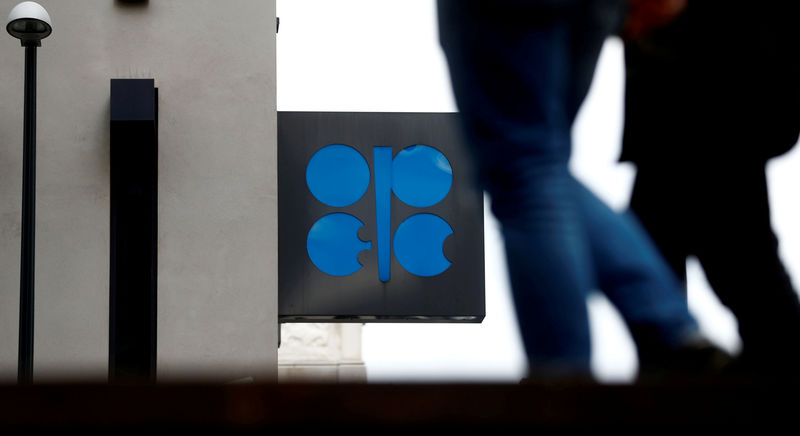 © Reuters. FILE PHOTO: People walk past the OPEC logo in front of its headquarters in Vienna