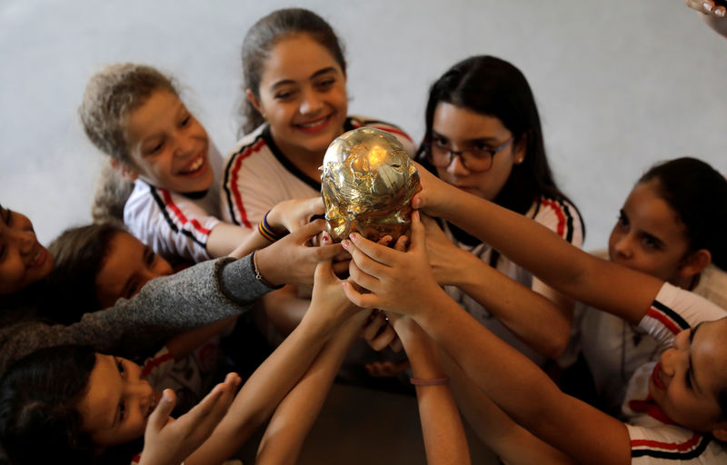 © Reuters. Students touch a replica of a FIFA World Cup trophy at the Football Museum in Sao Paulo