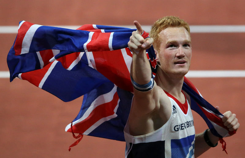 © Reuters. FILE PHOTO: Britain's Greg Rutherford gestures as he holds a Union flag behind him after winning the men's long jump final at the London 2012 Olympic Games at the Olympic Stadium