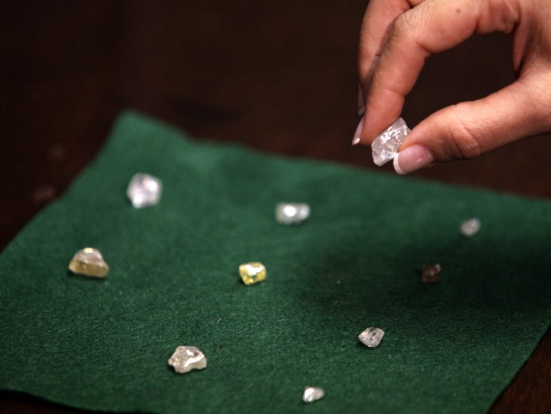 © Reuters. FILE PHOTO: A visitor holds a 17 carat diamond at a Petra Diamonds mine in Cullinan