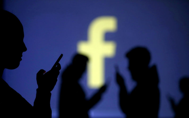 © Reuters. FILE PHOTO: Silhouettes of mobile users are seen next to a screen projection of Facebook logo in this picture illustration