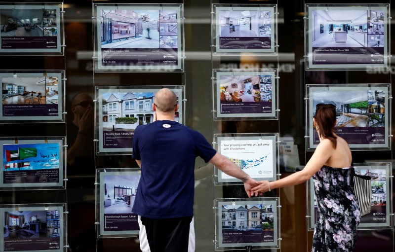 © Reuters. FILE PHOTO: A couple view properties for sale in an estate agents window in London