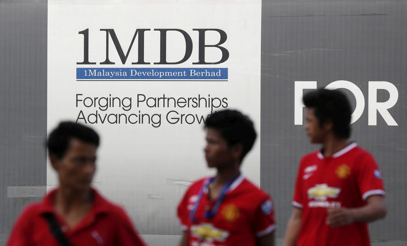 © Reuters. FILE PHOTO: Men walk past a 1 Malaysia Development Berhad (1MDB) billboard at the fund's flagship Tun Razak Exchange development in Kuala Lumpur