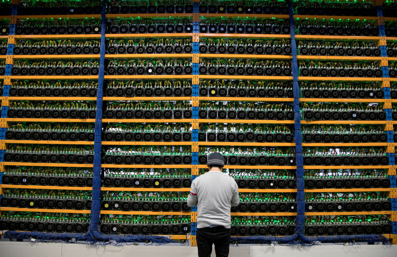 © Reuters. FILE PHOTO: A worker checks the fans on miners at the cryptocurrency farming operation Bitfarms in Farnham Quebec