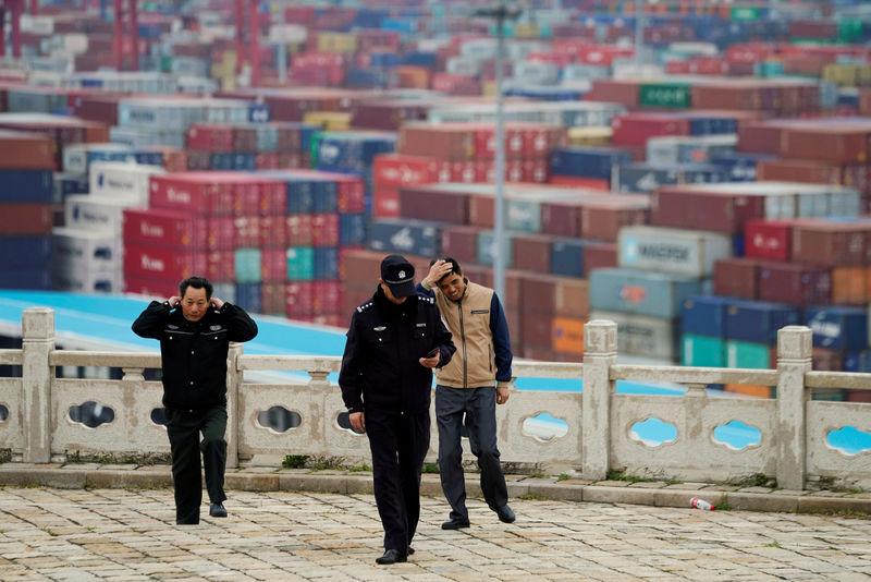 © Reuters. FILE PHOTO: Security guards walk in front of containers at the Yangshan Deep Water Port in Shanghai