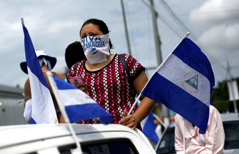 © Reuters. Manifestantes llevan banderas nacionales durante una protesta en Managua