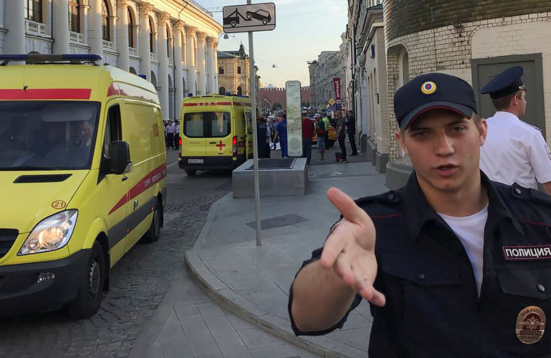 © Reuters. A police officer blocks the way as ambulances are parked near a damaged taxi, which ran into a crowd of people in central Moscow