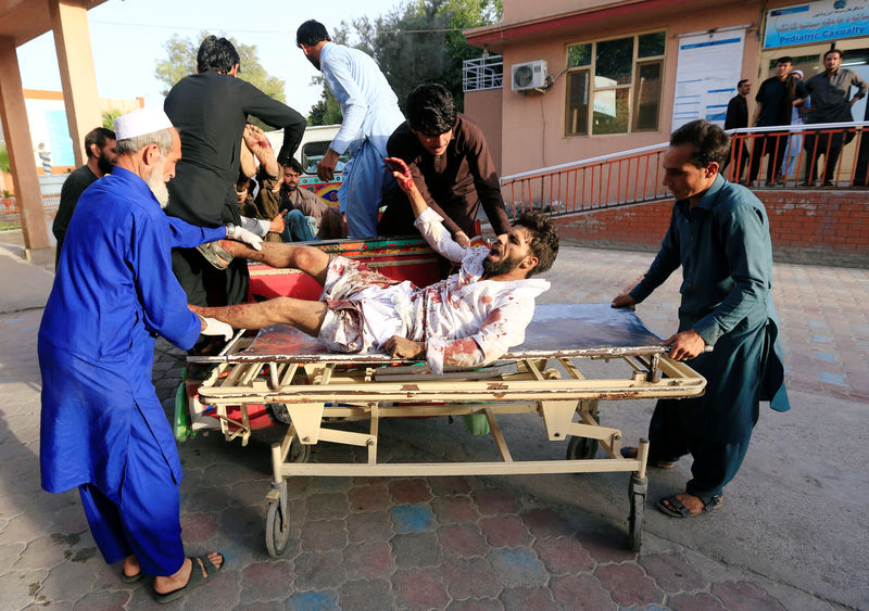 © Reuters. Un hombre traslada a un herido a un hospital tras la explosión de un cochebomba en Afganistán