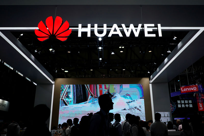 © Reuters. People walk past a sign board of Huawei at CES (Consumer Electronics Show) Asia 2018 in Shanghai