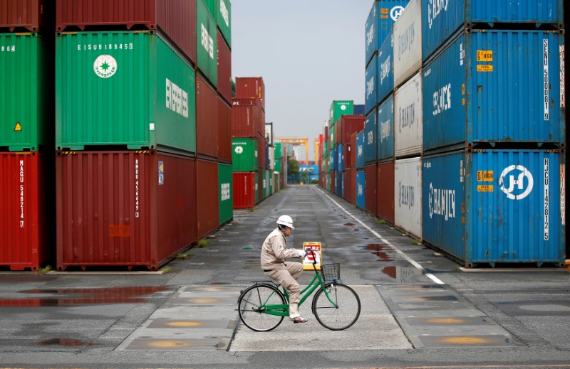 © Reuters. FILE PHOTO: A worker rides a bicycle in a container area at a port in Tokyo