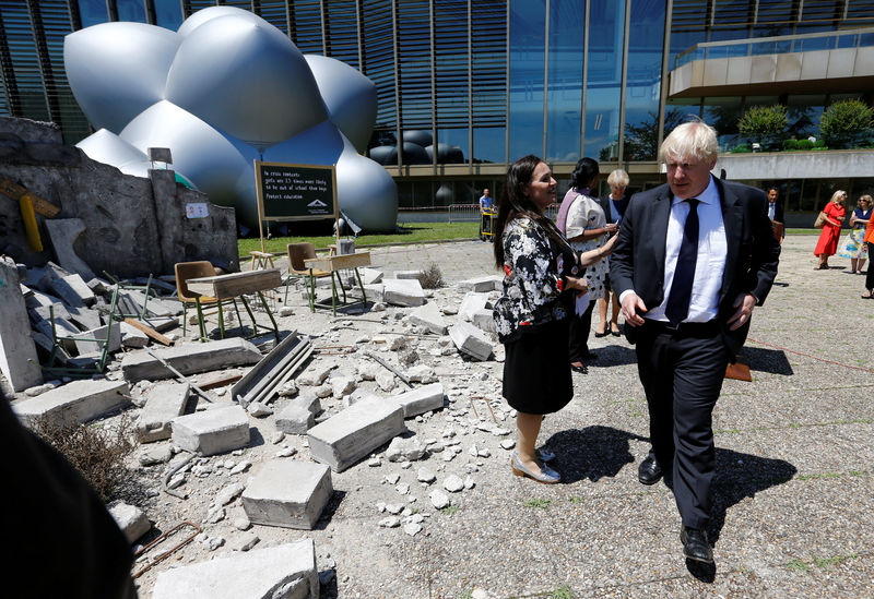 © Reuters. Britain's Foreign Secretary Johnson walks past a mockup of a bombed classroom in front of the Luminarium inflatable installation aside of the Human Rights Council at the United Nations in Geneva