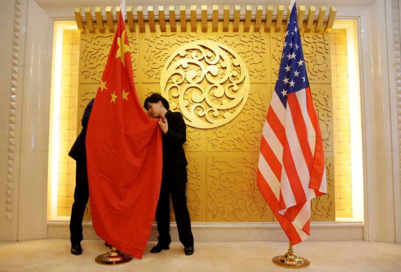 © Reuters. FILE PHOTO: Staff members set up Chinese and U.S. flags for a meeting between Chinese Transport Minister Li Xiaopeng and U.S. Secretary of Transportation Elaine Chao in Beijing