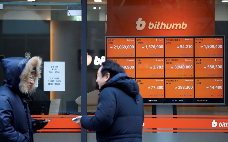 © Reuters. Men talk in front of an electric board showing exchange rates of various cryptocurrencies at Bithumb cryptocurrencies exchange in Seoul