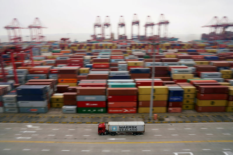 © Reuters. FILE PHOTO: A container truck moves past containers at the Yangshan Deep Water Port in Shanghai