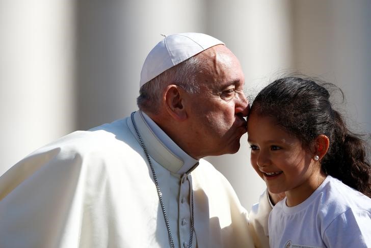 © Reuters. Papa Francesco dà un bacio a una bambina durante l'udienza generale del mercoledì a San Pietro, in Vaticano
