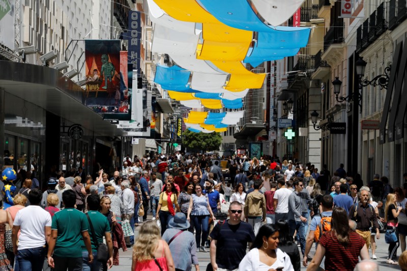 © Reuters. FILE PHOTO - People walk through one of the main pedestrian shopping areas, Preciados street, in central Madrid