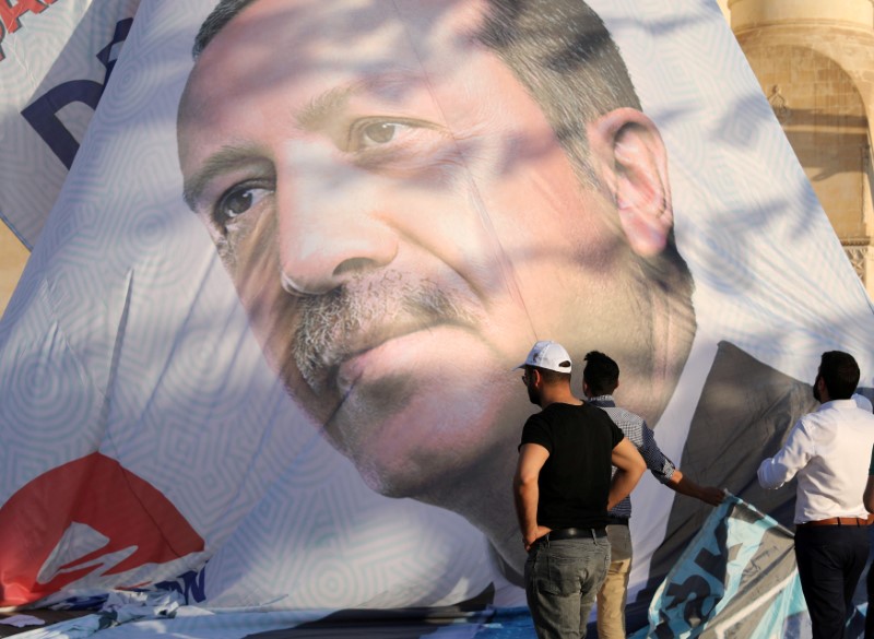 © Reuters. FILE PHOTO: Workers adjust a large election poster of President Tayyip Erdogan in Mardin