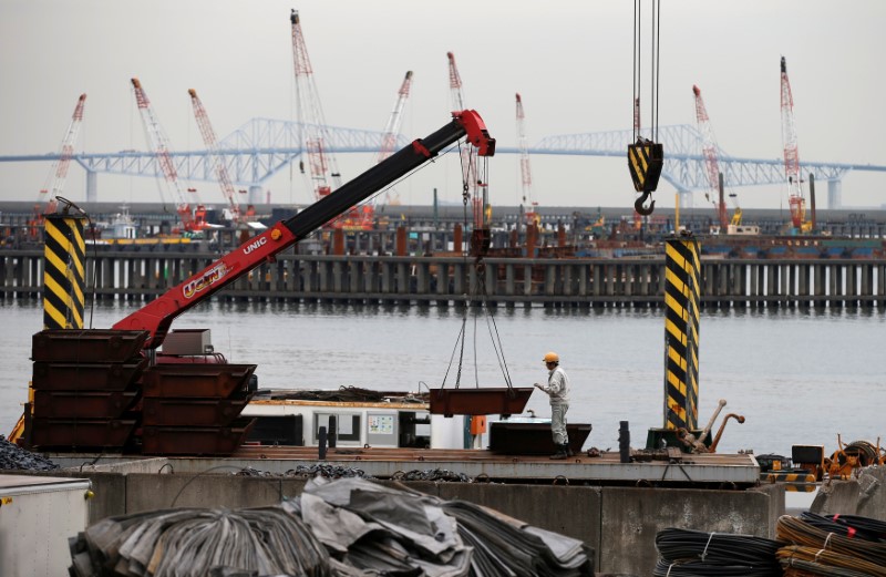 © Reuters. FILE PHOTO: A man works in front of cranes at an industrial area in Tokyo