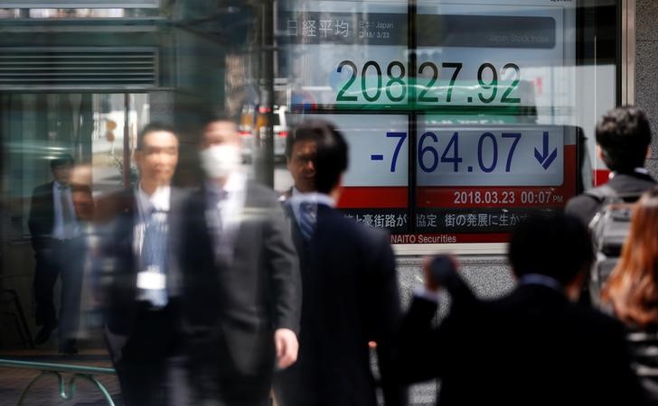 © Reuters. People walk past an electronic board showing Japan's Nikkei average outside a brokerage in Tokyo