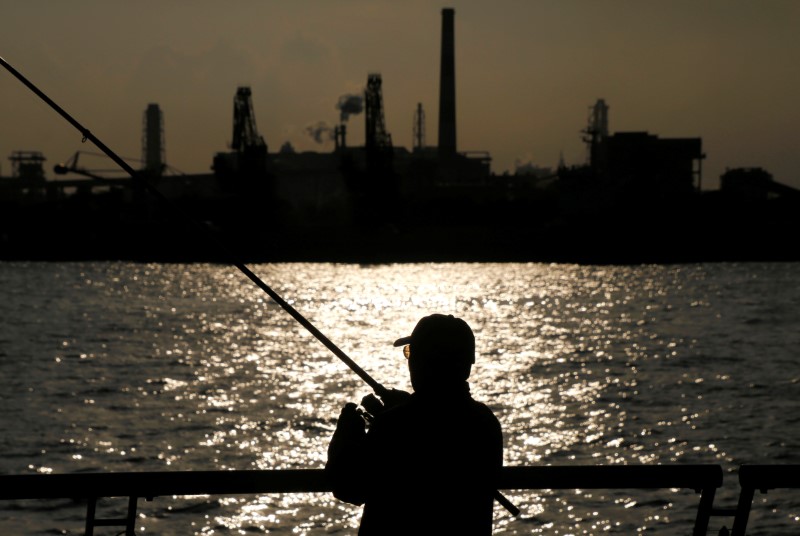 © Reuters. A man fishes near a factory at the Keihin industrial zone in Kawasaki, Japan