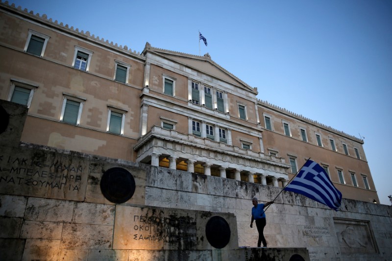 © Reuters. FILE PHOTO: A man waves a Greek flag during an anti-goverment rally outside the Greek parliament building in Athens
