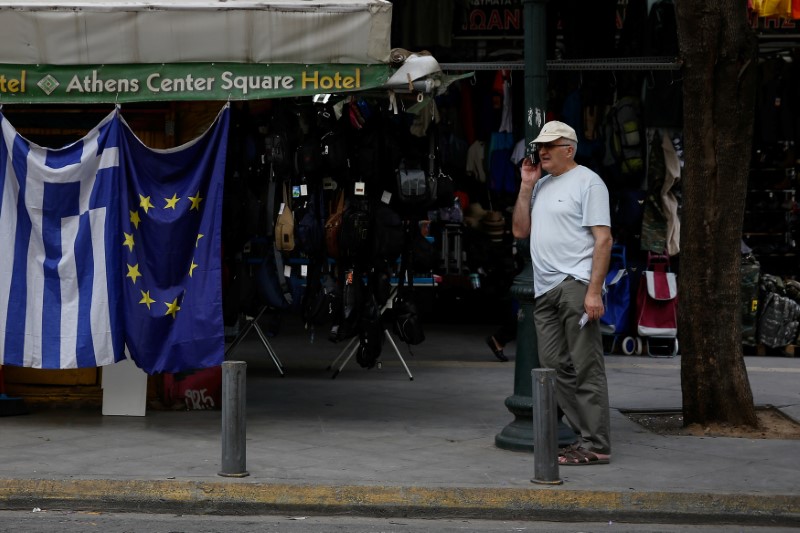 © Reuters. A man stands next to a kiosk selling Greek and EU flags in Athens