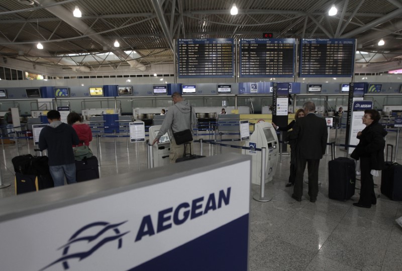 © Reuters. FILE PHOTO -  Commuters stand in front of electronic check-in machines of Aegean airlines inside Athens' Eleftherios Venizelos airport