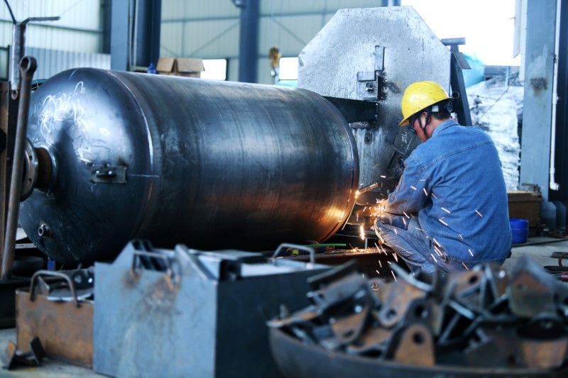 © Reuters. Worker welds a pressure vessel at a company manufacturing industrial equipment in Nantong