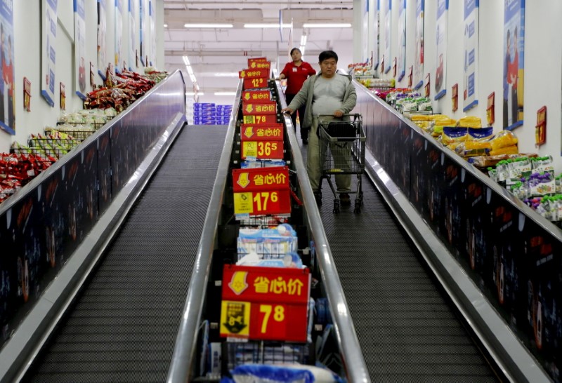 © Reuters. Shoppers ride on a travelator at a supermarket in Beijing