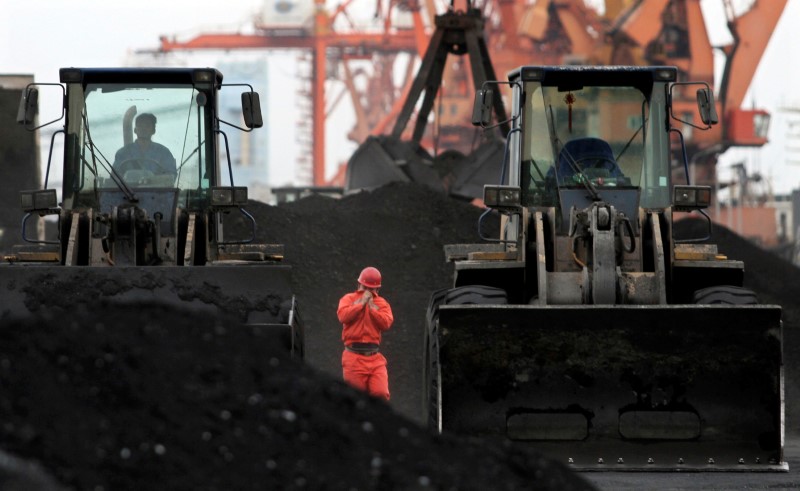 © Reuters. FILE PHOTO - An employee walks between front-end loaders which are used to move coal imported from North Korea at Dandong port in the Chinese border city of Dandong