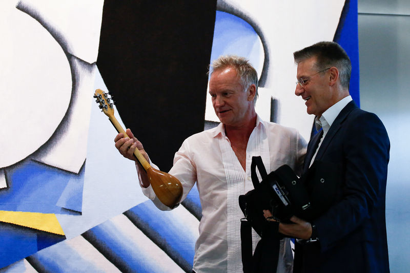 © Reuters. Athens International Airport CEO Yiannis Paraschis gives a ''baglama'', a traditional Greek instrument, as a gift to British singer Sting during an event organised by Amnesty International and the Athens International Airport in Athens