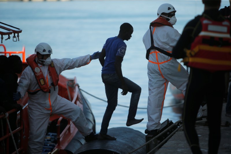 © Reuters. A migrant is helped by a rescuer after arriving on a rescue boat at the port of Malaga