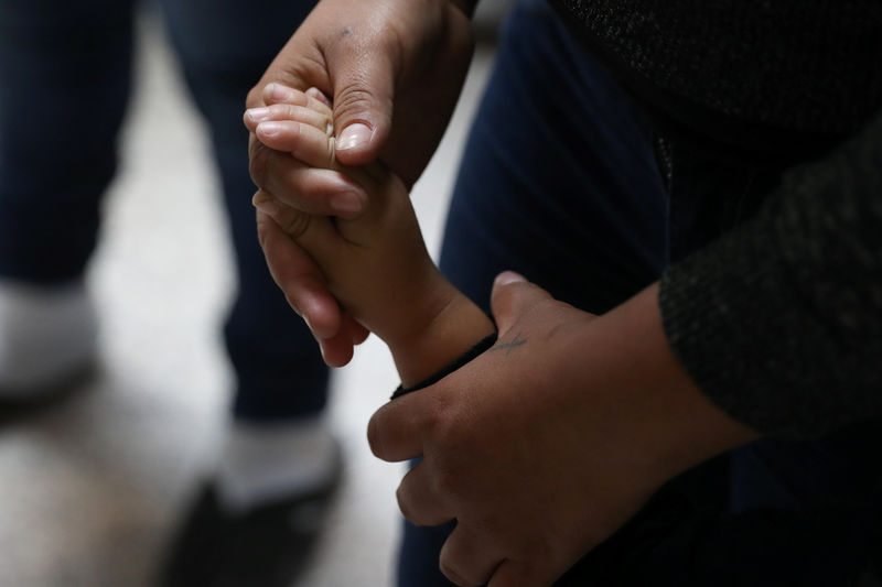 © Reuters. A woman holds a child's hand as undocumented immigrant families are released from detention at a bus depot in McAllen
