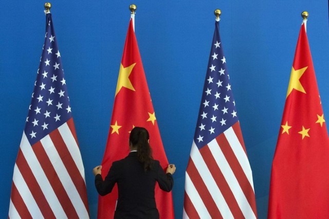 © Reuters. Foto del archivo: Una mujer china ajusta una bandera de su país junto a otras banderas estadounidenses antes de una reunión ampliada del Diálogo Estratégico, parte del Diálogo Estratégico y Económico Estados Unidos-China celebrada en Pekín, China